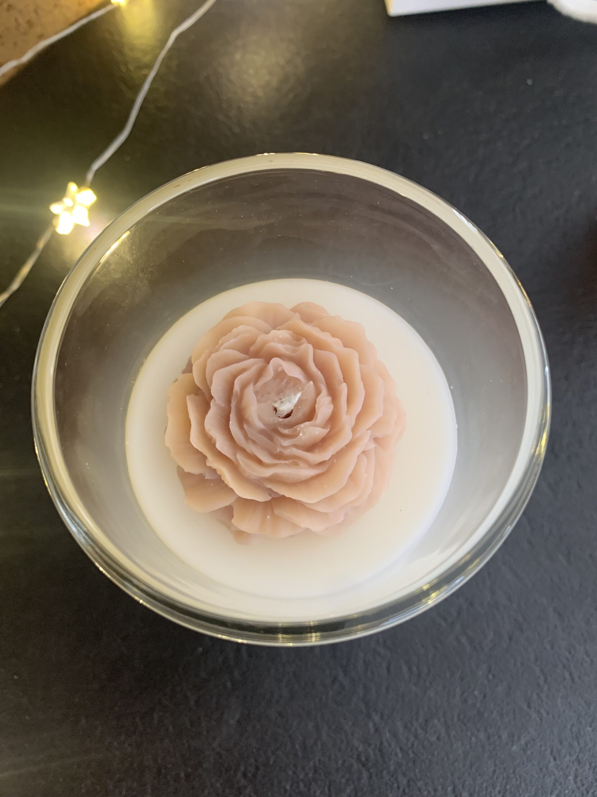Bougie Tonka vue du dessus avec fleur beige rosé en cire et mèche centrée