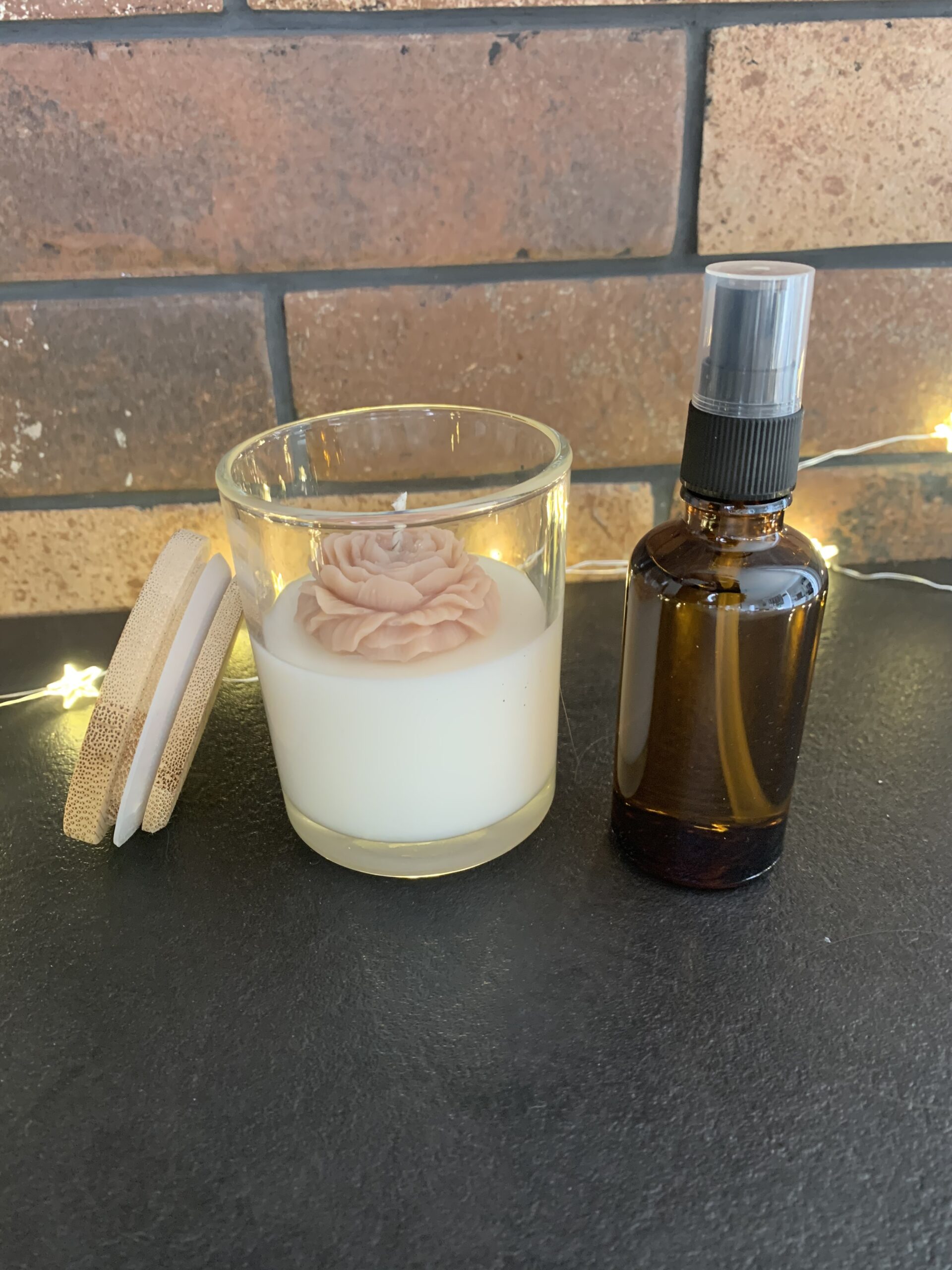 Bougie Tonka avec couvercle en bois posé à côté et fleur beige rosé